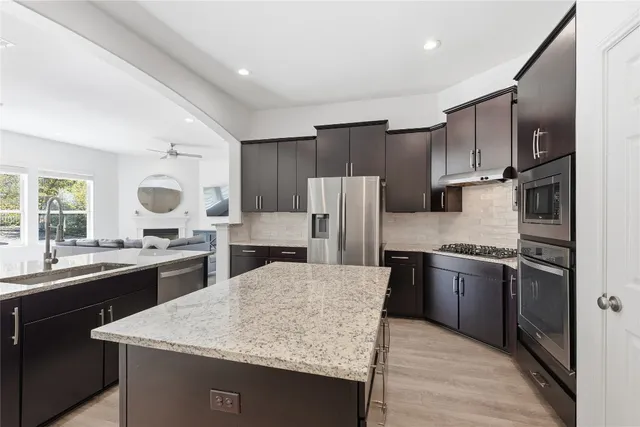 a kitchen with stainless steel appliances granite countertop a sink a stove and a refrigerator