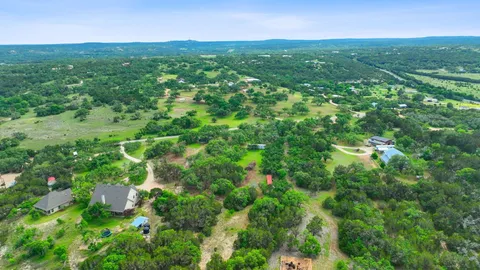 an aerial view of residential houses with outdoor space and trees