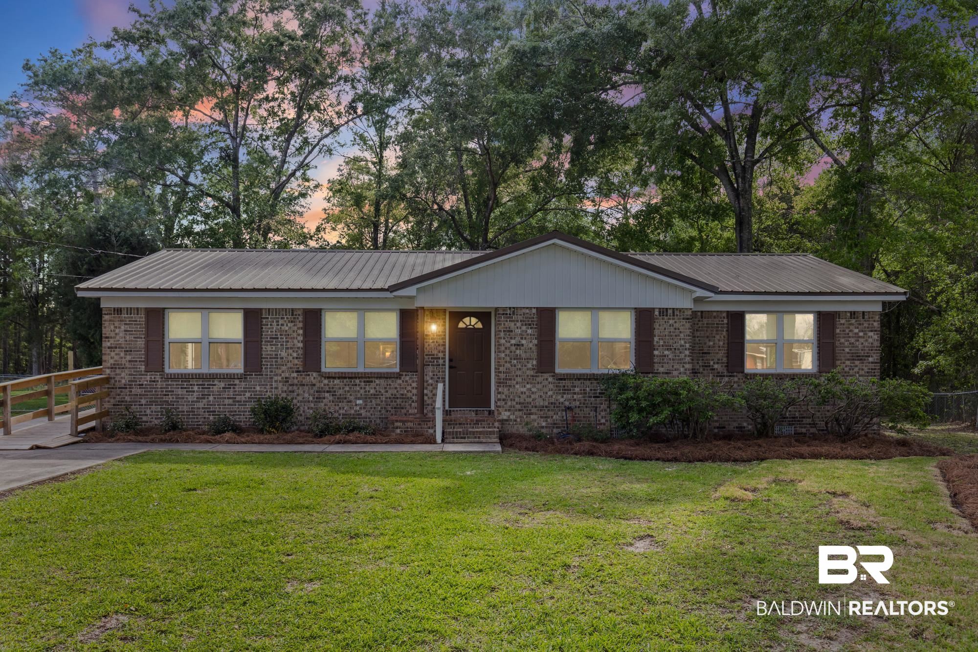 6701 Lott Road Semmes, AL 36575 - Photo 1 of 24 Ranch-style house featuring a metal roof, brick siding, a lawn, and view of scattered trees