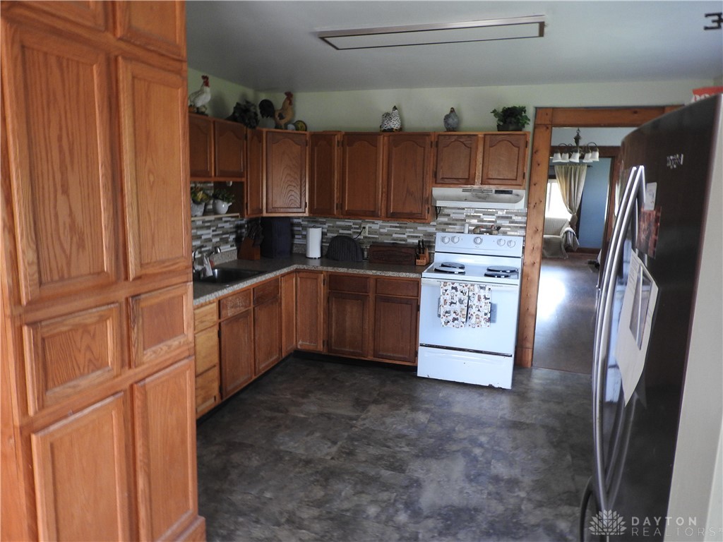 2105 East Loy Road Piqua, OH 45356 - Photo 10 of 26 This kitchen features rich wooden cabinetry and contemporary tile, offering functional elegance for everyday living.