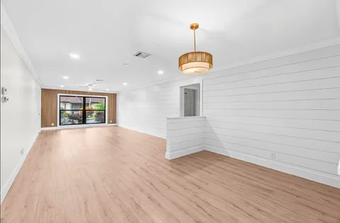 a view of empty room with wooden floor and chandelier