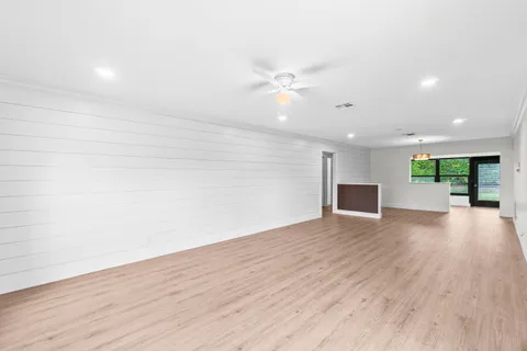 an empty room with wooden floor and ceiling fan