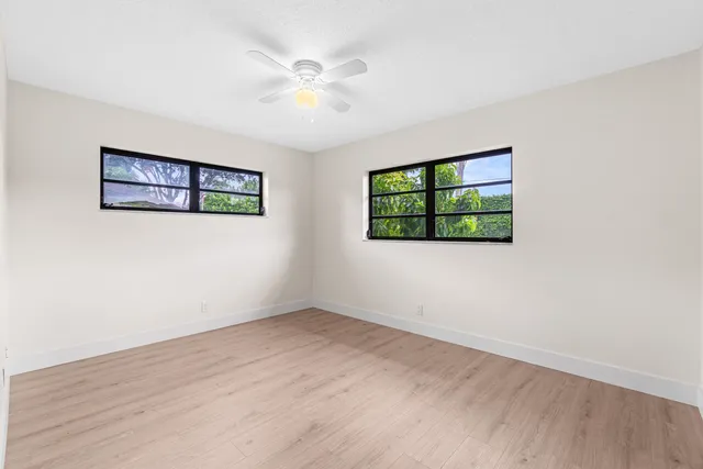 an empty room with wooden floor and windows