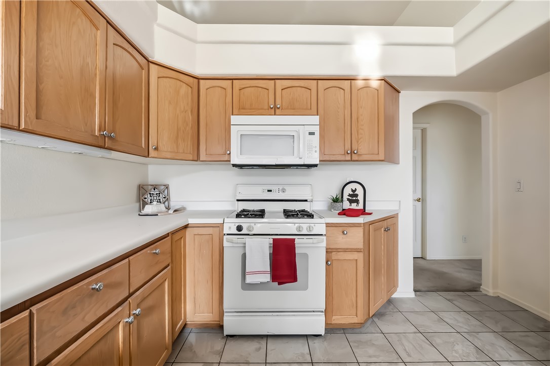 2853 Winchester Road Bullhead City, AZ 86442 - Photo 19 of 40 Kitchen featuring wood-finish cabinetry, white countertops, and white appliances including a built-in microwave and gas range