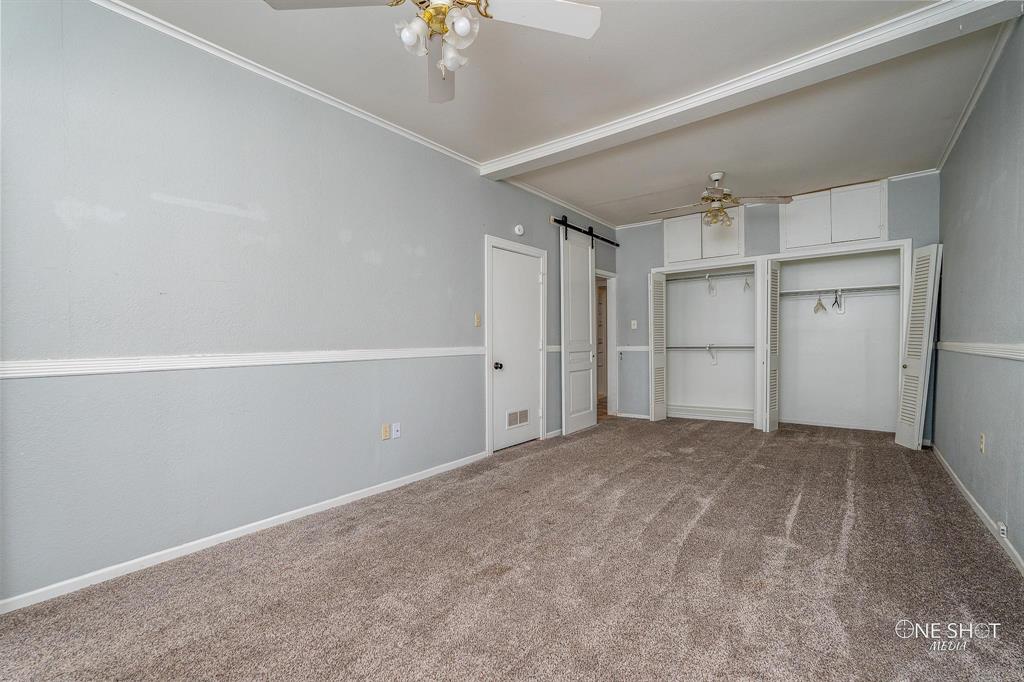 3741 Caldwell Road Abilene, TX 79601 - Photo 19 of 36 Unfurnished living room featuring a barn door, crown molding, ceiling fan, and carpet floors