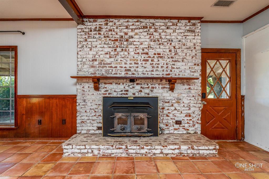 3741 Caldwell Road Abilene, TX 79601 - Photo 5 of 36 Interior details featuring a brick fireplace, wood walls, and ornamental molding