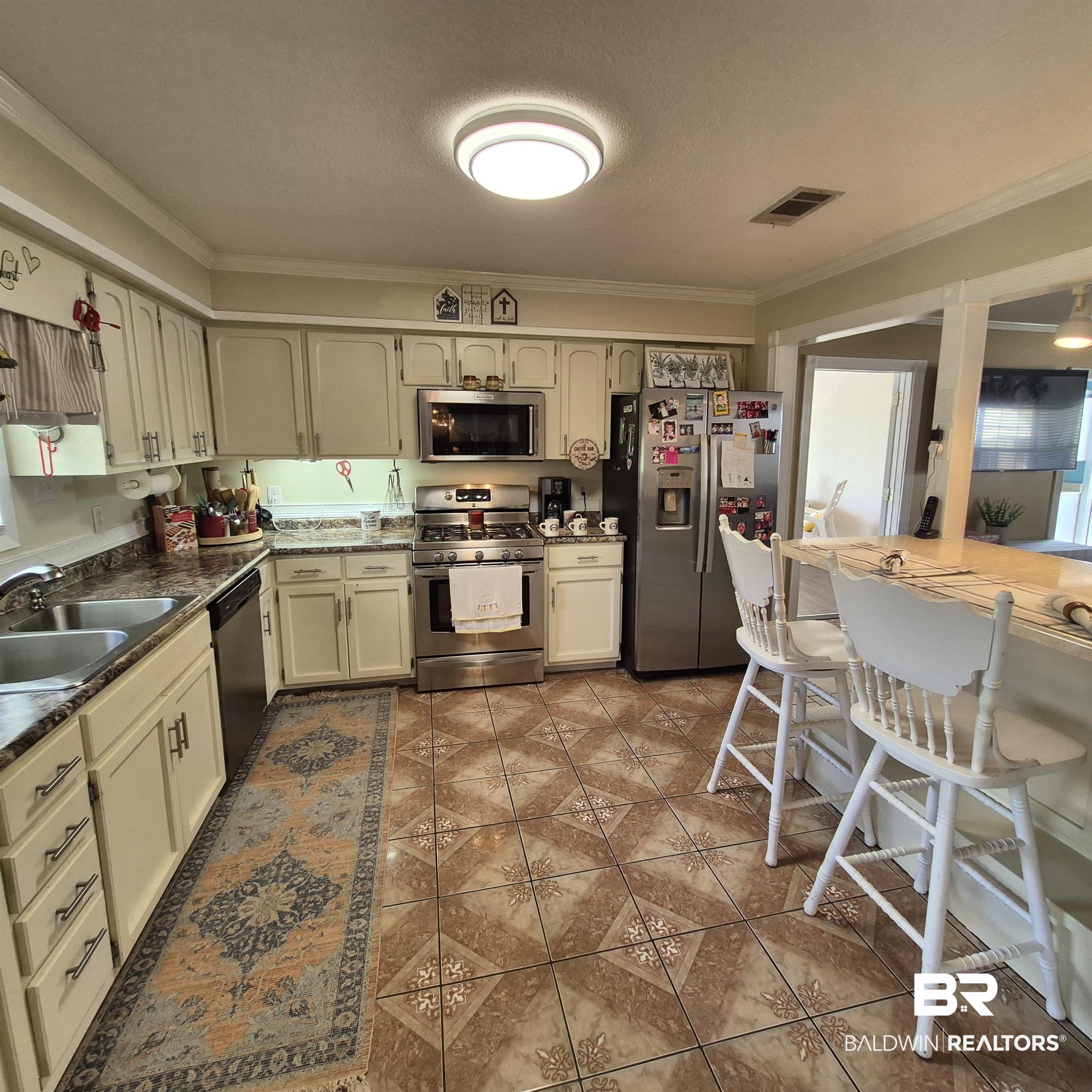 26635 Highway 41 Range, AL 36473 - Photo 15 of 74 Kitchen featuring ornamental molding, stainless steel appliances, dark countertops, a breakfast bar area, and a textured ceiling
