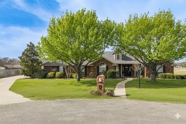 a view of a house with a big yard and large trees