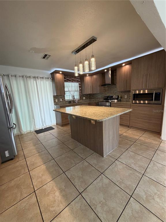 101 Gardenia Road Kissimmee, FL 34743 - Photo 5 of 24 a kitchen with stainless steel appliances a stove a sink and a refrigerator