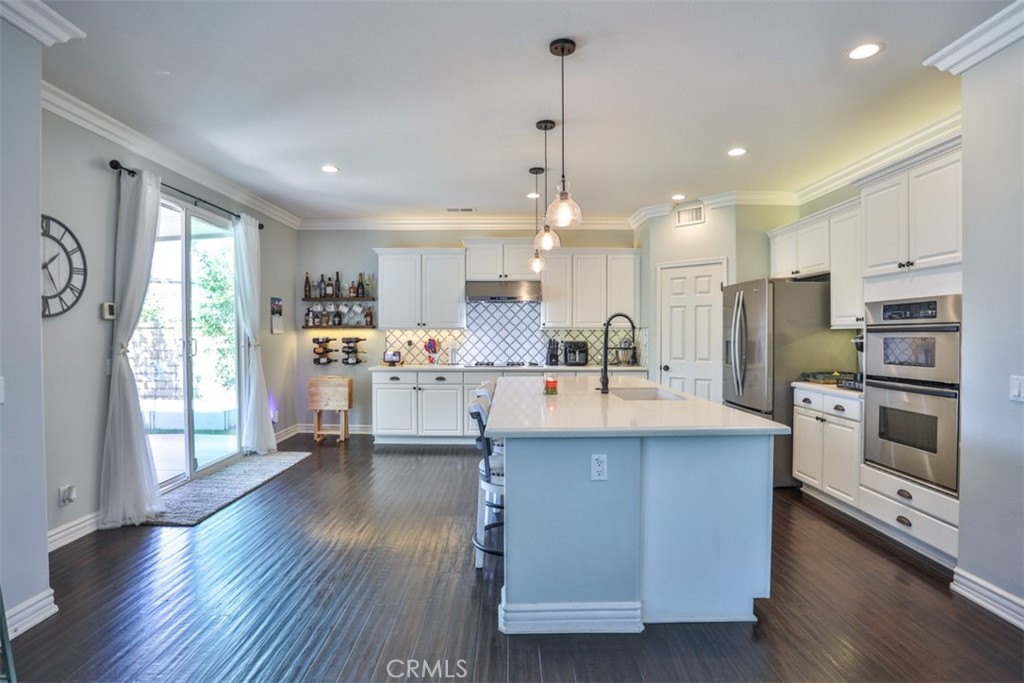 3250 Quartz Circle Corona, CA 92882 - Photo 13 of 68 a kitchen with stainless steel appliances kitchen island granite countertop a stove a sink a refrigerator and white cabinets with wooden floor