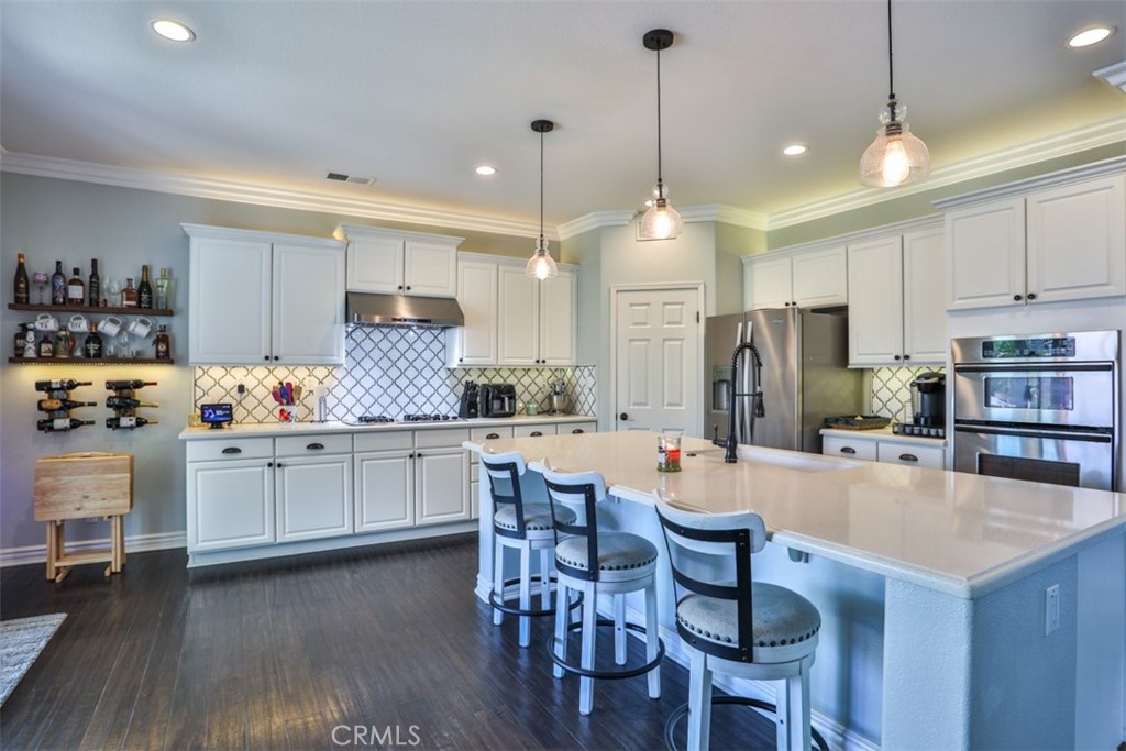 3250 Quartz Circle Corona, CA 92882 - Photo 14 of 68 a kitchen with stainless steel appliances a dining table chairs stove refrigerator and cabinets