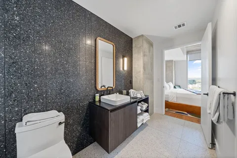 a bathroom with a granite countertop sink a toilet and mirror