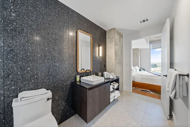 a bathroom with a granite countertop sink a toilet and mirror