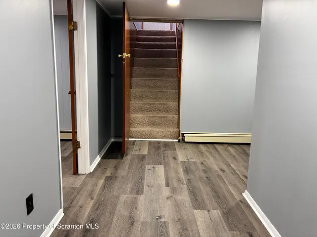 a view of an empty room with wooden floor and a window