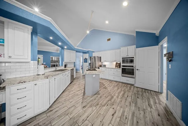 a large kitchen with cabinets wooden floor and stainless steel appliances