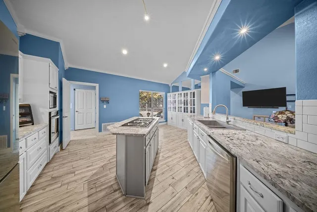 a large kitchen with stainless steel appliances granite countertop a lot of counter space and wooden floor