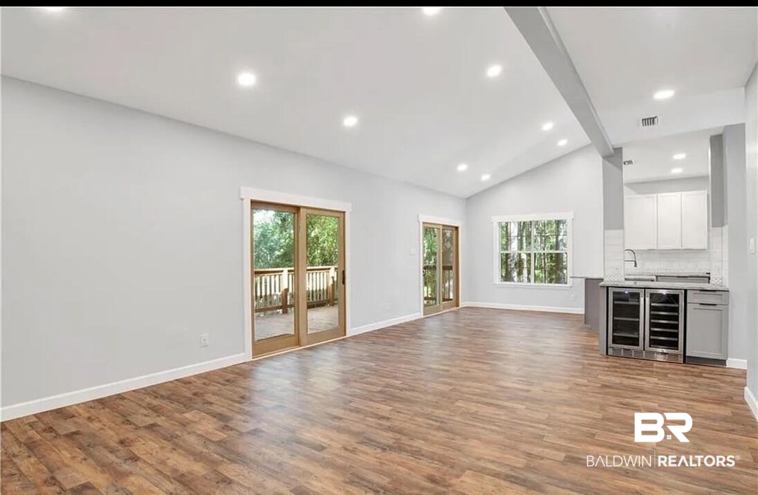 632 Ridgewood Drive Daphne, AL 36526 - Photo 16 of 36 Unfurnished living room with vaulted ceiling with beams, sink, wine cooler, and light hardwood / wood-style floors