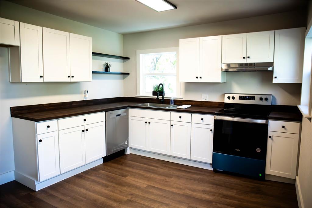 a kitchen with stainless steel appliances granite countertop white cabinets a sink and dishwasher with wooden floor