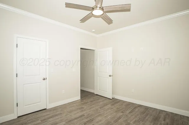 an empty room with wooden floor and ceiling fan