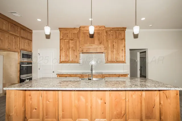 a kitchen with kitchen island granite countertop kitchen island stainless steel appliances a sink and a counter top space