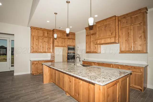 a kitchen with stainless steel appliances granite countertop a sink a oven and a wooden cabinets