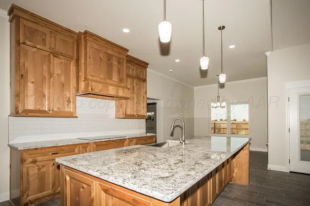 a kitchen with kitchen island granite countertop wooden cabinets and a sink