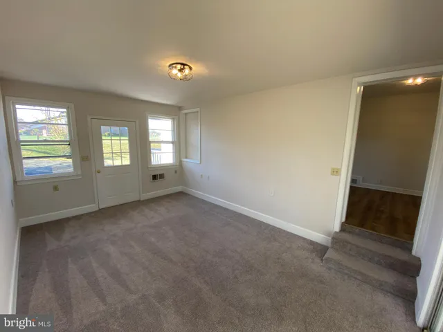 a view of an empty room with window and bathroom
