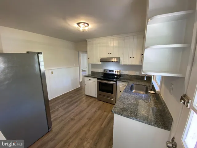 a kitchen with granite countertop a refrigerator stove and sink