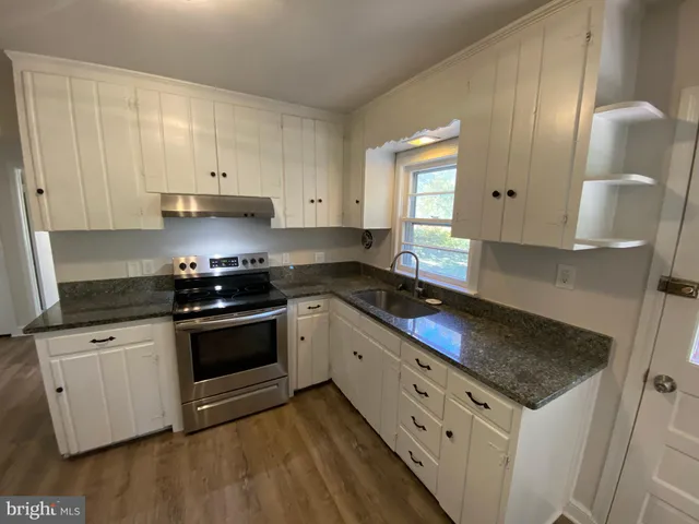 a kitchen with granite countertop white cabinets and white appliances