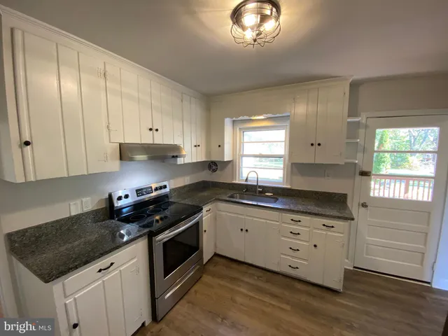 a kitchen with granite countertop white cabinets and white appliances