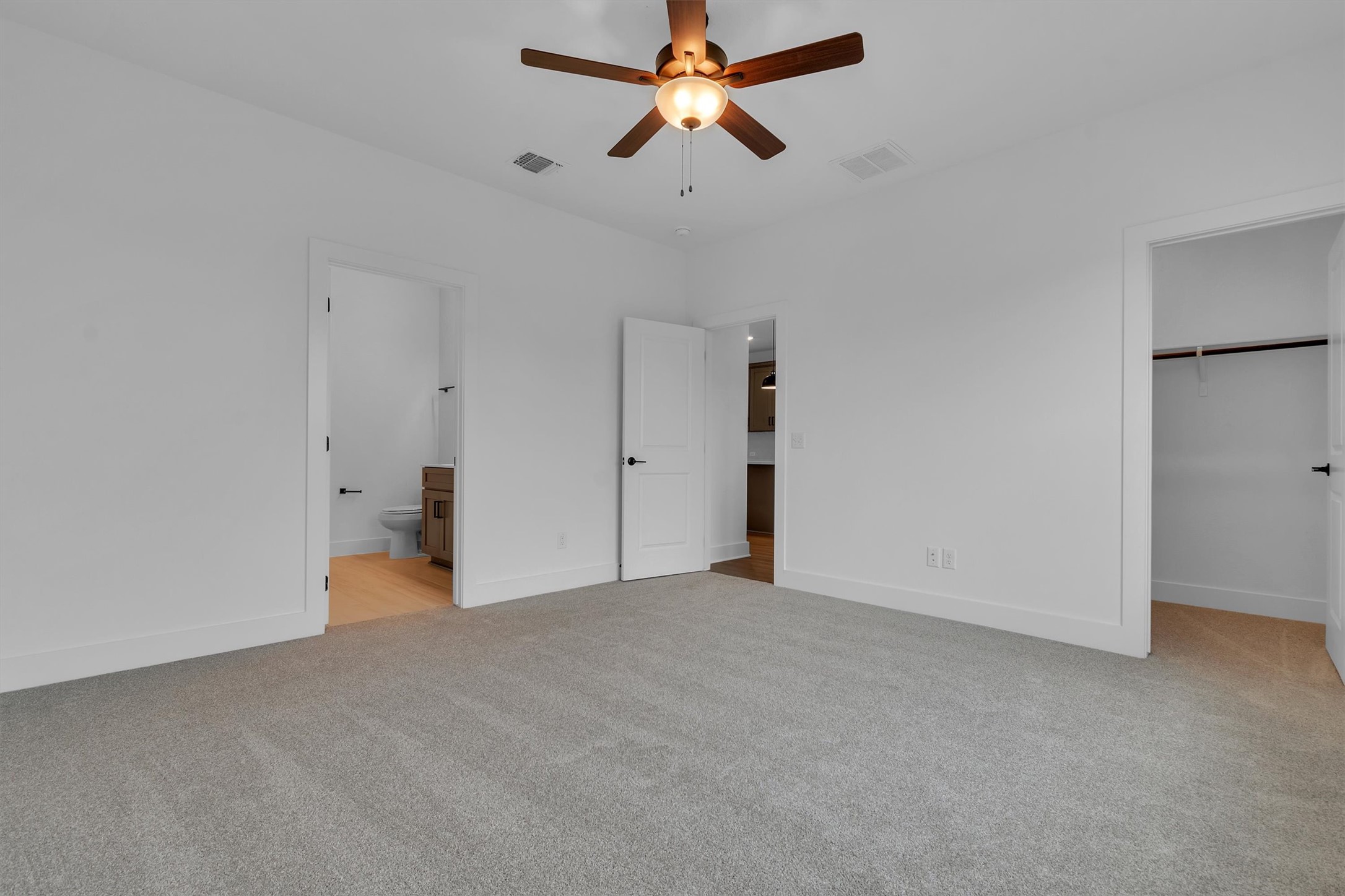 368 Bridge Deck Loop Kyle, TX 78640 - Photo 26 of 40 Unfurnished bedroom featuring light carpet, a walk in closet, baseboards, connected bathroom, and a closet