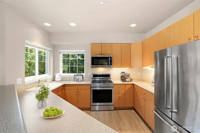a kitchen with stainless steel appliances a stove top oven a refrigerator and a sink