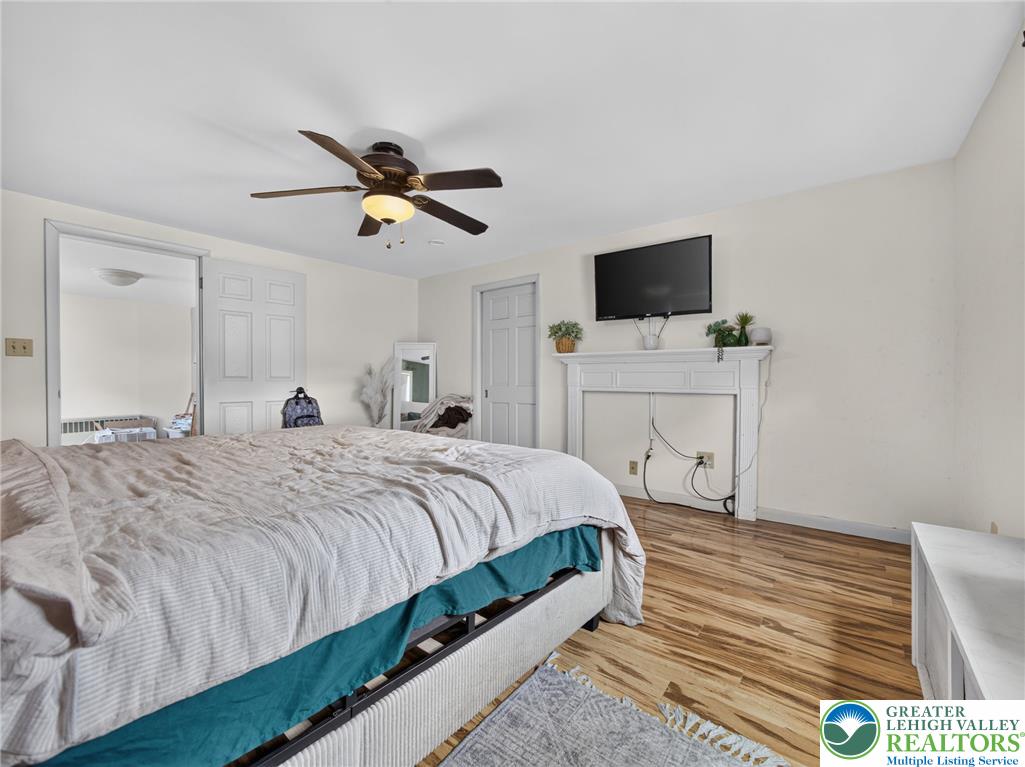2628 Levans Road Coplay, PA 18037 - Photo 45 of 54 A well-lit bedroom with rich wood flooring and a classic white fireplace mantel.