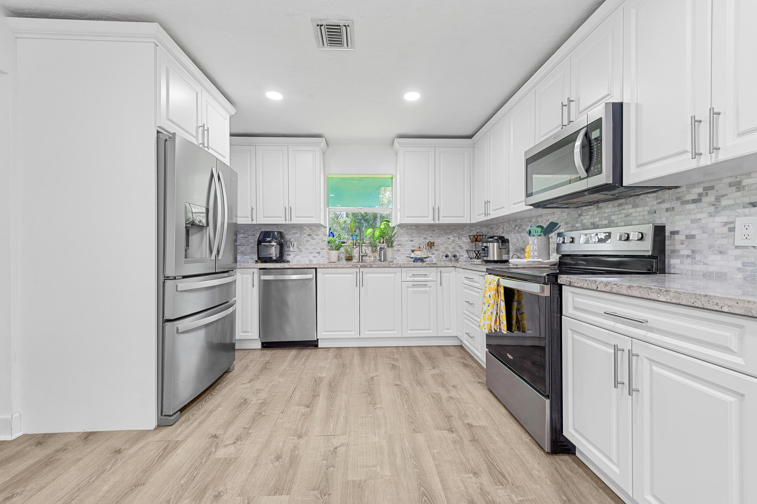 12450 77th Street Fellsmere, FL 32948 - Photo 22 of 44 a kitchen with granite countertop a refrigerator oven a sink dishwasher and white cabinets with wooden floor