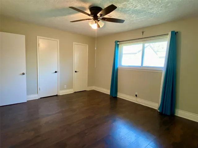an empty room with wooden floor and windows with curtains