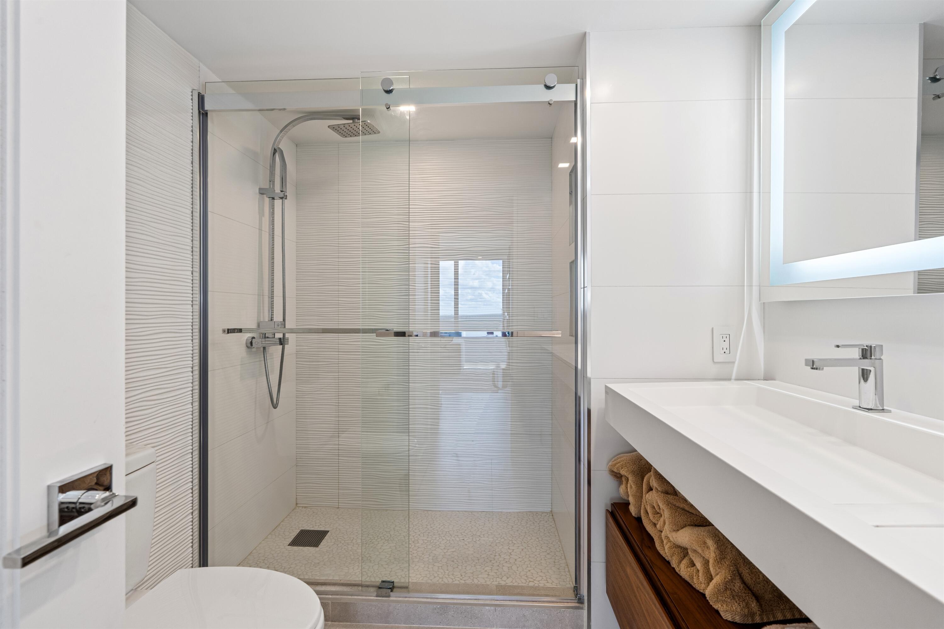 2600 South Ocean Boulevard, Unit 19E Boca Raton, FL 33432 - Photo 25 of 53 a bathroom with a shower sink vanity mirror and toilet