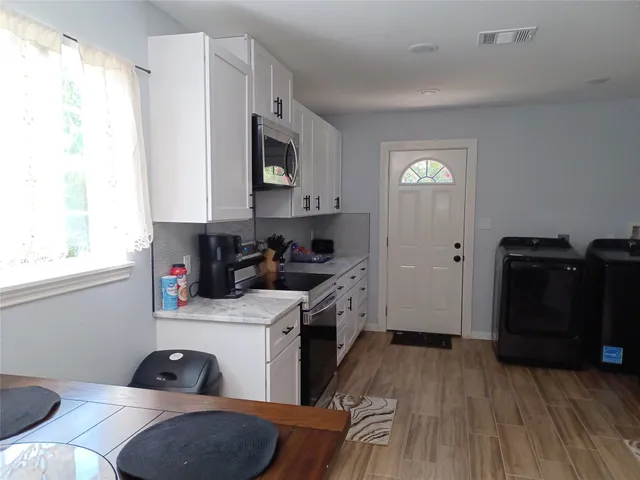 a kitchen with stainless steel appliances granite countertop a sink cabinets and wooden floor