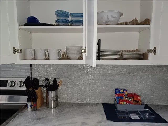 a kitchen with white cabinets and stove