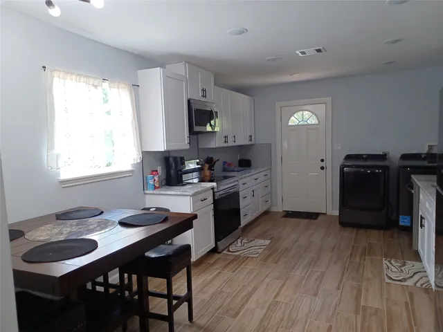 a kitchen with white cabinets and window