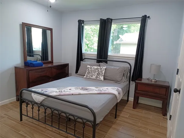 a view of a hallway with wooden floor and a bathroom