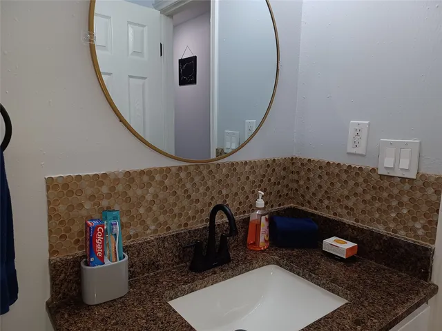 a bathroom with a granite countertop sink and a mirror