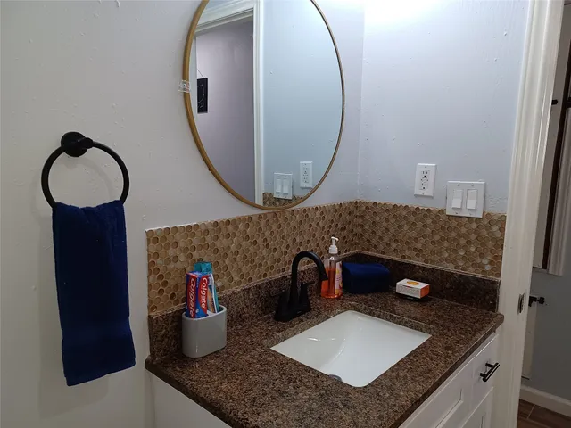 a bathroom with a granite countertop sink and a mirror