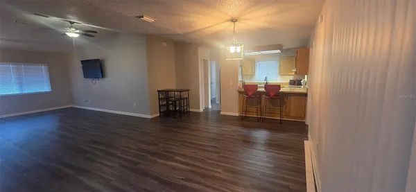 an empty room with wooden floor chandelier fan and windows