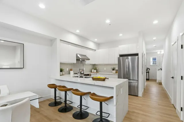 a kitchen with stainless steel appliances a dining table chairs and refrigerator