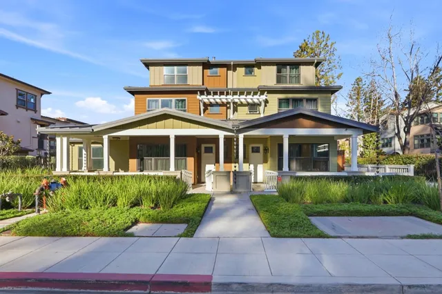 a front view of a house with a yard and potted plants