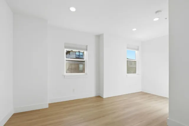 an empty room with wooden floor and windows