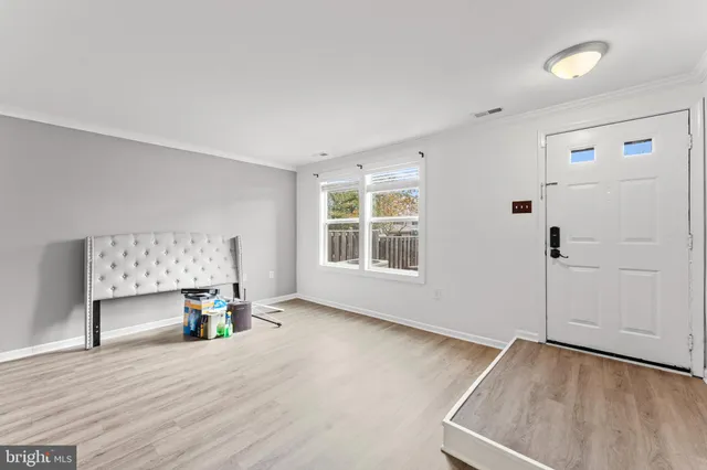 a view of an empty room with a window and wooden floor