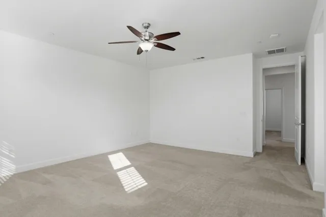 an empty room with a ceiling fan and window