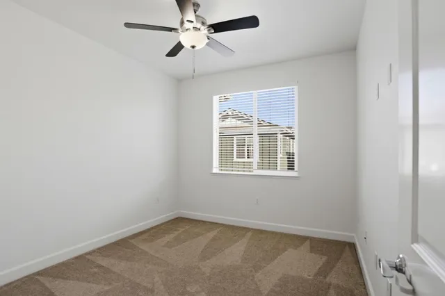 an empty room with a window and a fan