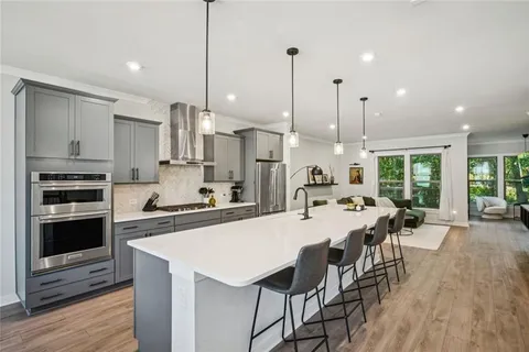 a kitchen with stainless steel appliances kitchen island granite countertop a sink a refrigerator and chairs